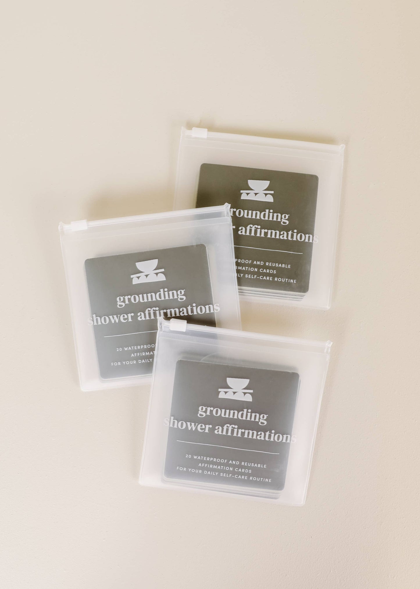 Three packages of 'grounding shower affirmation' on a beige background