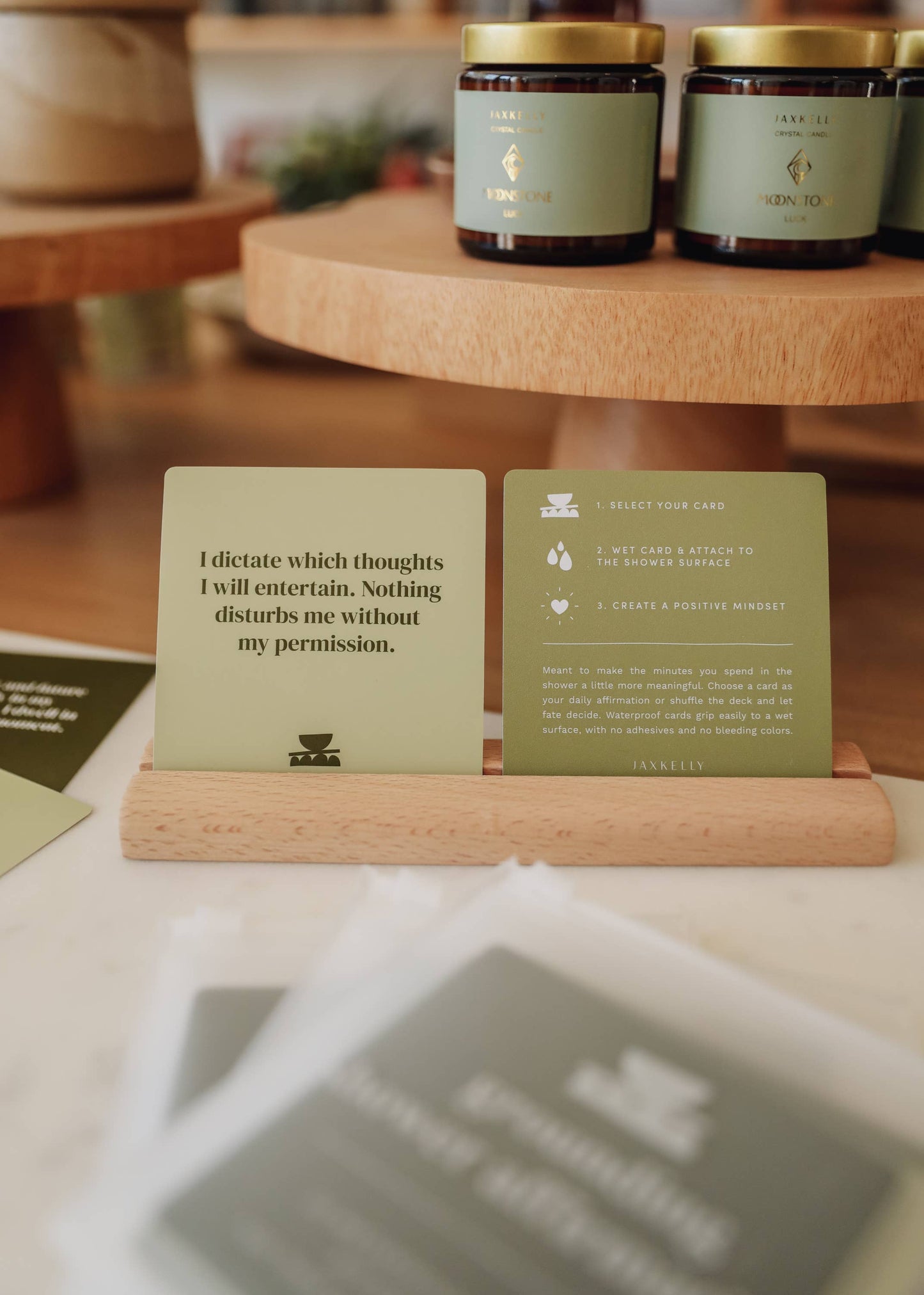 Two green cards with text on a wooden stand, with jars in the background.
