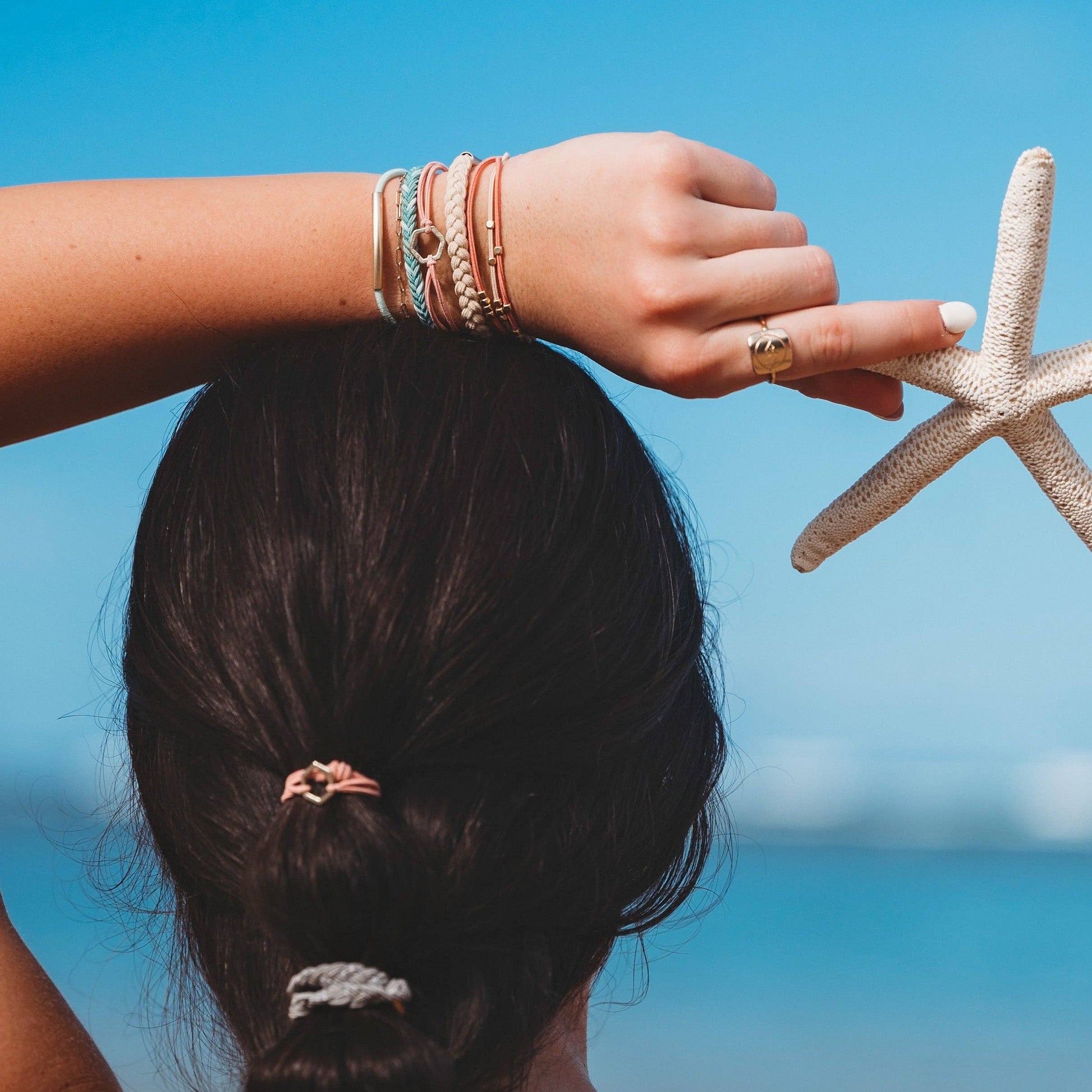 Person holding a starfish with a blurred beach background. K'lani “live”