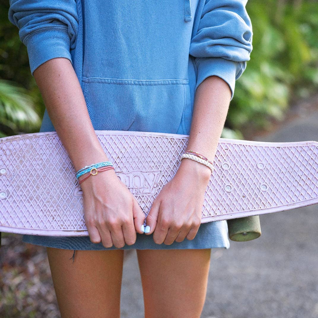 K'lani model holding a skateboard with a blurred green background